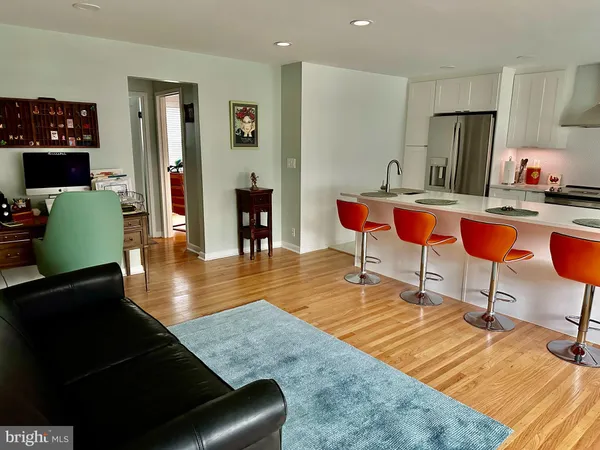 a living room with furniture a rug and a refrigerator