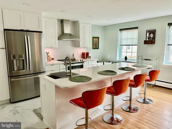 a kitchen with stainless steel appliances granite countertop a dining table chairs refrigerator and sink