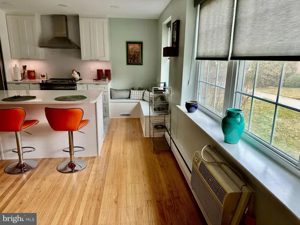 a kitchen with stainless steel appliances kitchen island granite countertop wooden floors and large window