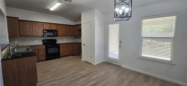 a kitchen with stainless steel appliances granite countertop a refrigerator a sink dishwasher a stove and a dining table with wooden floor