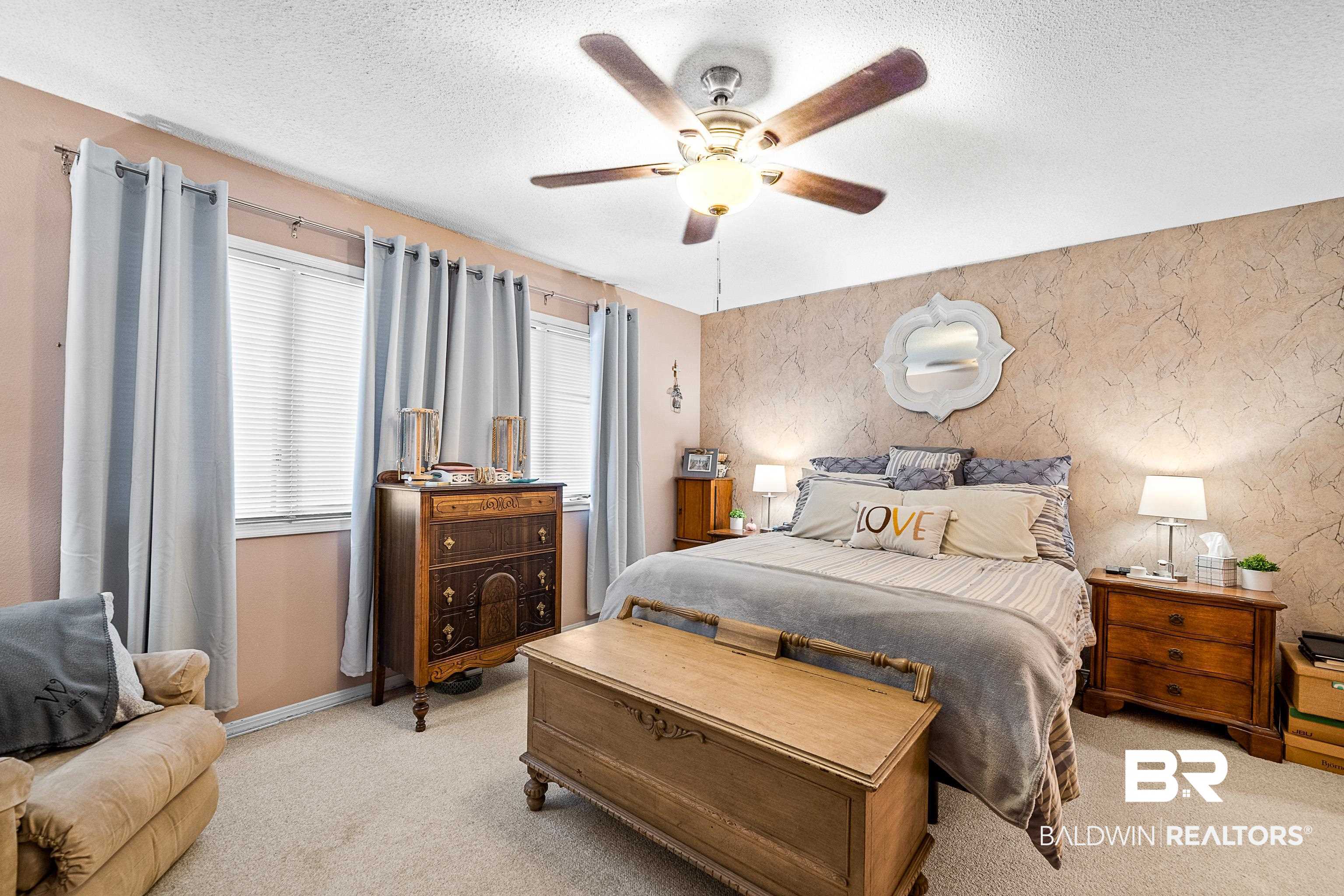 1701 Regency Road, Unit 106 Gulf Shores, AL 36542 - Photo 6 of 42 Bedroom featuring a textured ceiling, light carpet, wallpapered walls, ceiling fan, and an accent wall