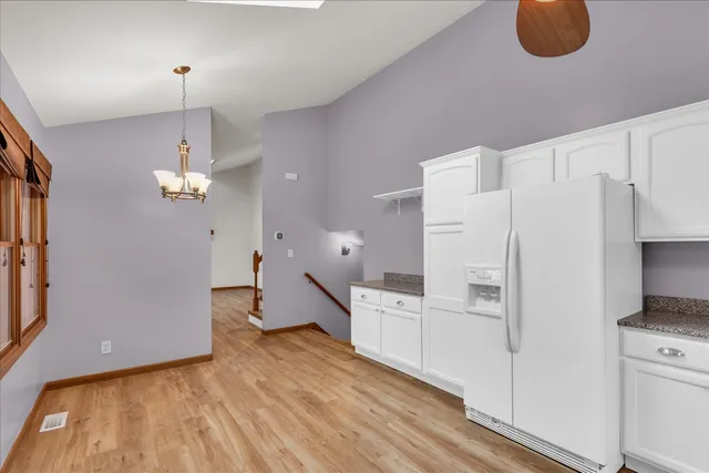 a open kitchen with white cabinets and refrigerator