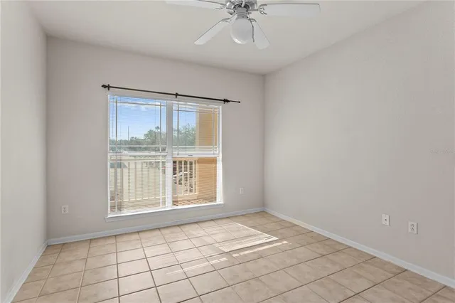 an empty room with chandelier fan and windows