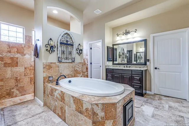 a bathroom with a tub a sink and mirror