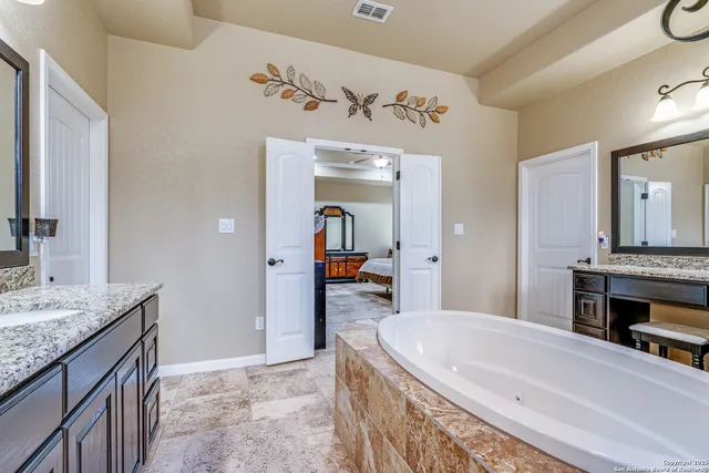 a en suite bathroom with a granite countertop double vanity sink and a mirror