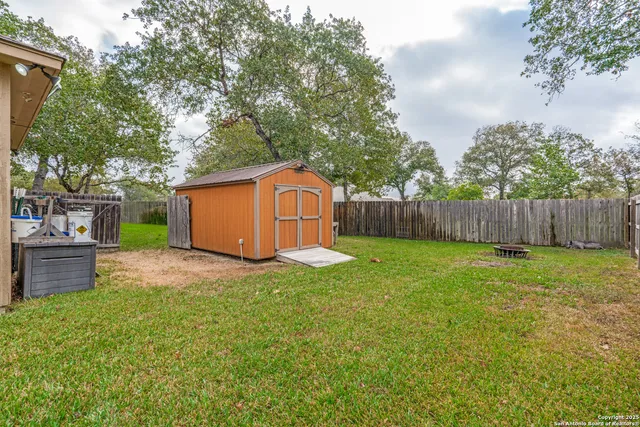 a view of a backyard with large trees and wooden fence