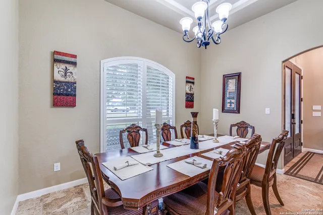a view of a dining room with furniture a chandelier and a window