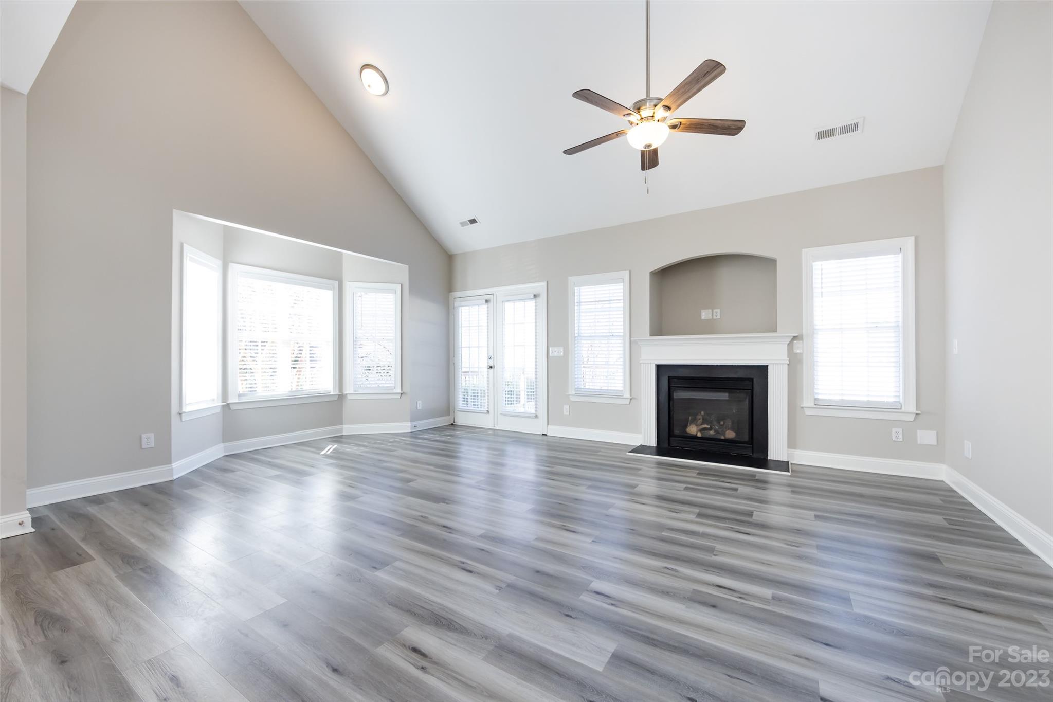 18909 Ruffner Drive Cornelius, NC 28031 - Photo 7 of 22 an empty room with wooden floor a fireplace a ceiling fan and windows
