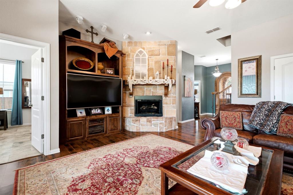600 Aspen Street Pilot Point, TX 76258 - Photo 7 of 39 Living area featuring hardwood flooring, a stone-clad fireplace with a natural wood mantel, a built-in media center with shelving, a ceiling fan, and recessed lighting