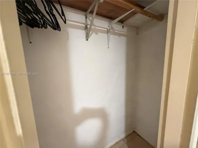 a view of a refrigerator in kitchen and an empty room with wooden floor