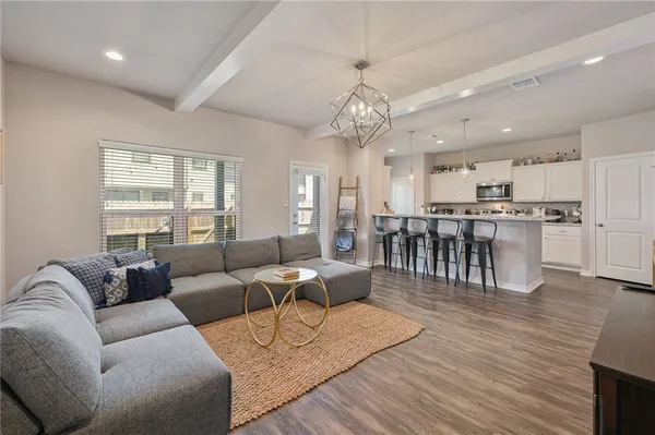 a living room with furniture kitchen view and a wooden floor