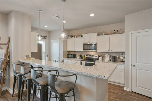 a kitchen with stainless steel appliances granite countertop a stove top oven a sink refrigerator and cabinets