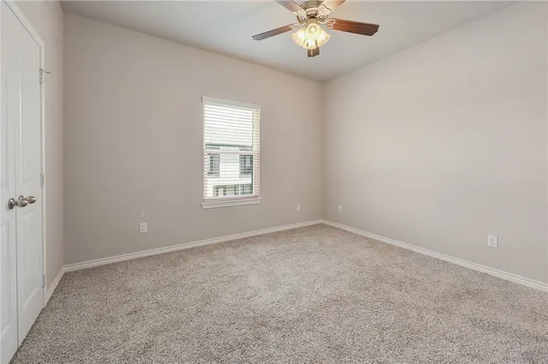 an empty room with a chandelier fan and windows