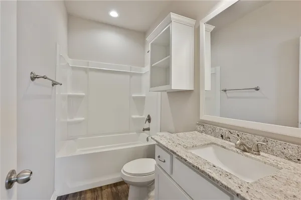 a bathroom with a granite countertop sink a toilet and shower