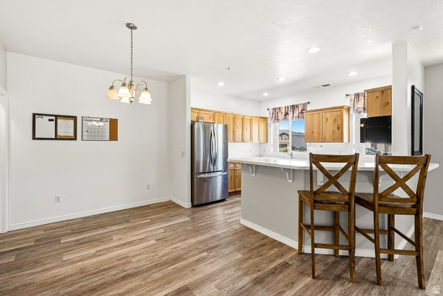 1177 Northfield Road, Unit 26 Cedar City, UT 84721 - Photo 8 of 45 Open-concept dining area with wood-finish flooring, a contemporary chandelier, recessed lighting, and a breakfast bar with a solid surface countertop