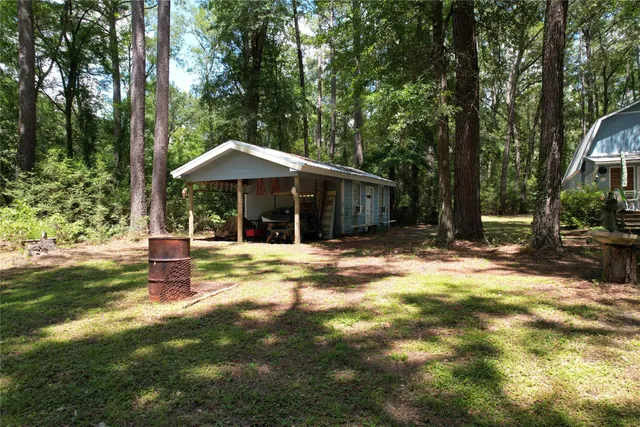 a backyard of a house with table and chairs under an umbrella