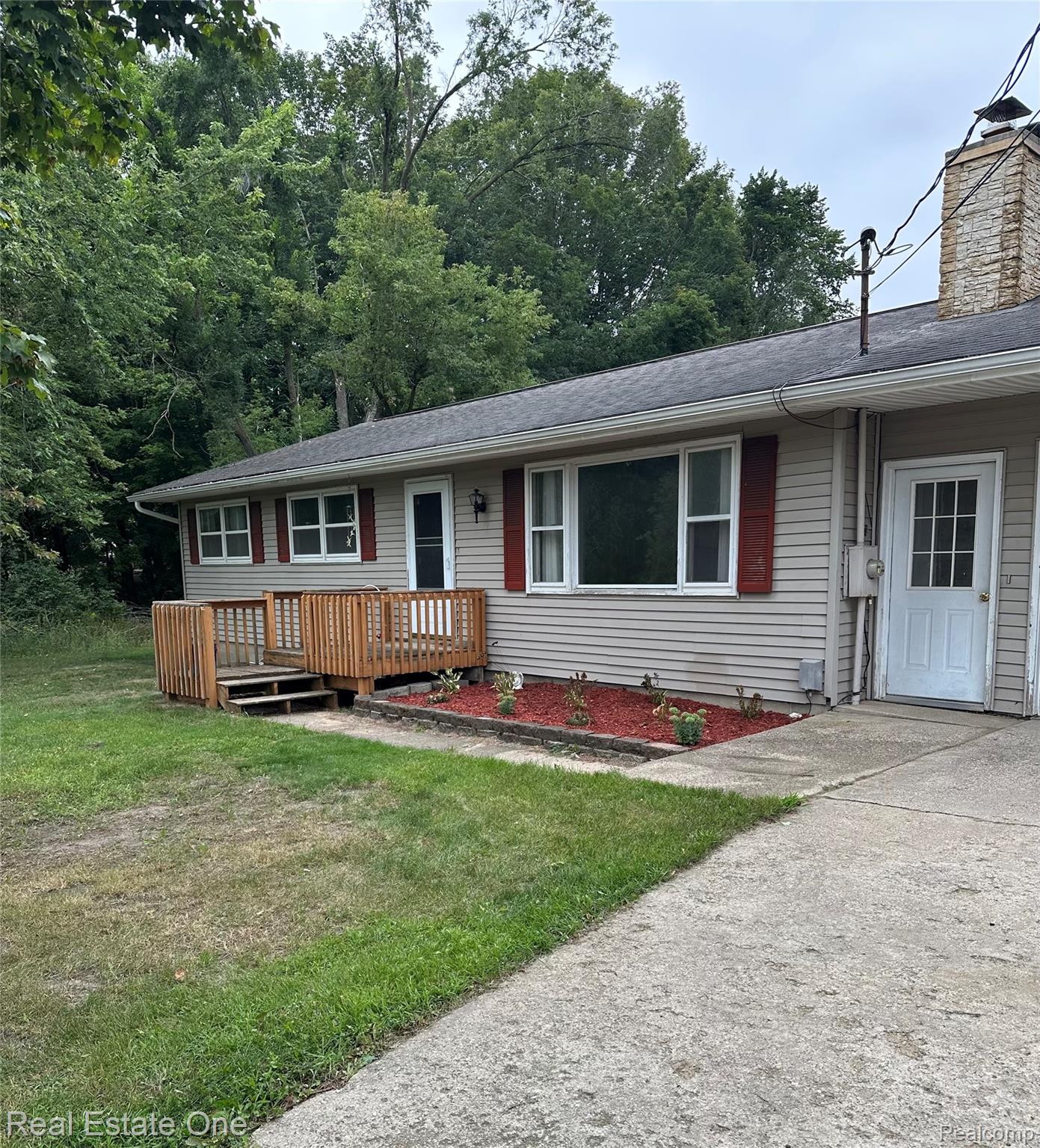 2430 Coolidge Road Barryton, MI 49305 - Photo 1 of 29 Siding exterior with red window shutters, a wooden deck, and a concrete driveway