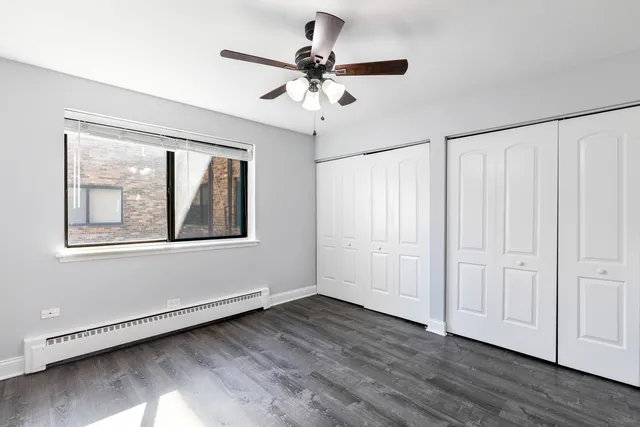 an empty room with wooden floor chandelier fan and windows