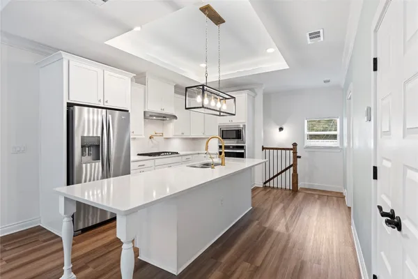 a kitchen with kitchen island a wooden floor and white appliances