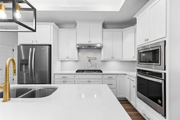 a kitchen with stainless steel appliances granite countertop a stove a refrigerator and a stove top oven