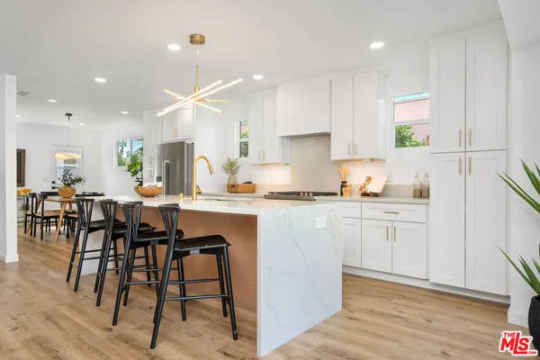 a kitchen with stainless steel appliances kitchen island granite countertop a table chairs sink and cabinets