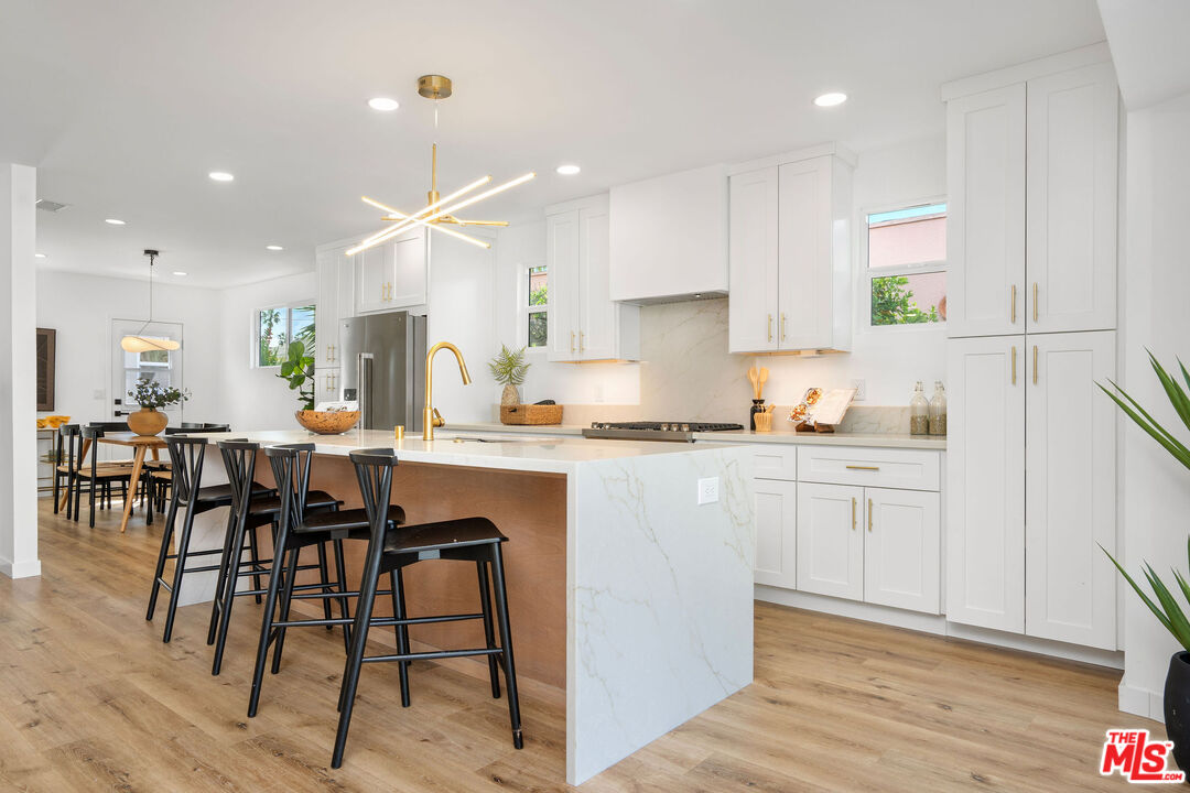 5418 South Rimpau Boulevard Los Angeles, CA 90043 - Photo 5 of 23 a kitchen with stainless steel appliances kitchen island granite countertop a table chairs sink and cabinets