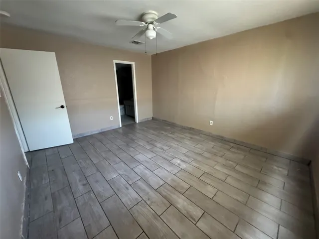 an empty room with wooden floor and ceiling fan