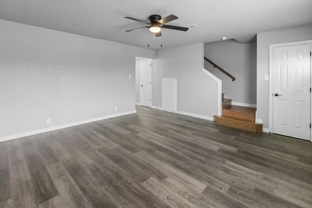 a view of empty room with wooden floor and ceiling fan