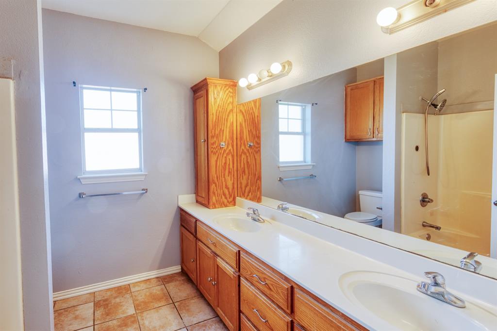 216 East Walcott Street Pilot Point, TX 76258 - Photo 6 of 12 a bathroom with a double vanity sink a mirror and a shower