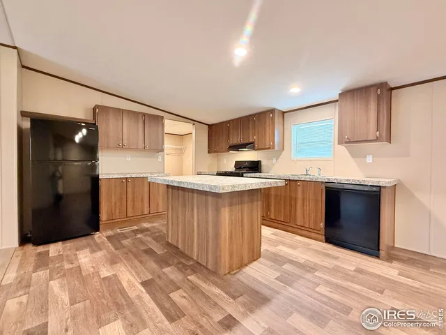 a kitchen with stainless steel appliances kitchen island granite countertop a refrigerator and a sink
