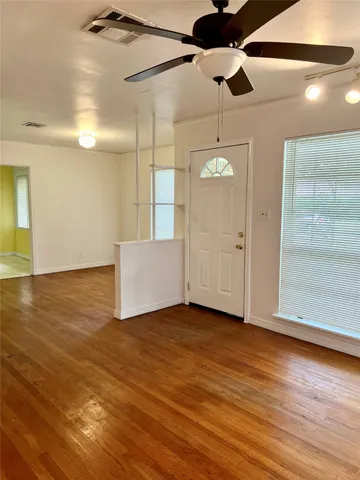 a view of an empty room with window and wooden floor