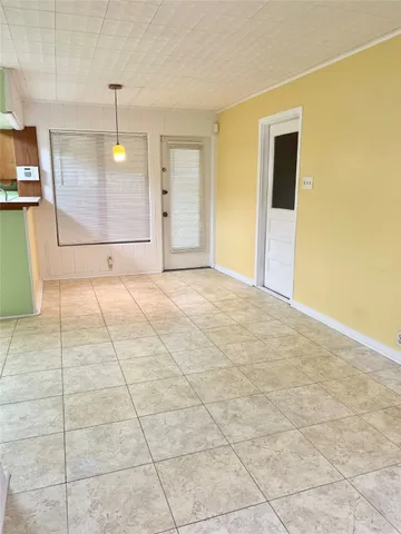 a view of an empty room with kitchen and a window