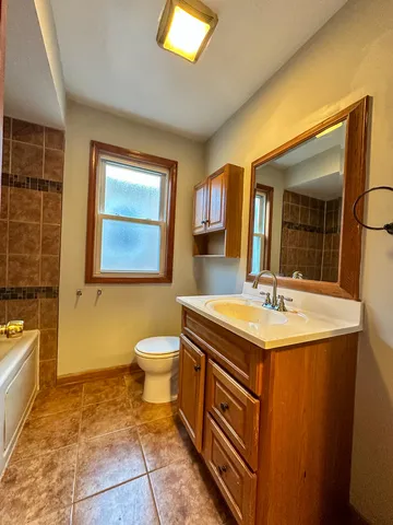a bathroom with a granite countertop sink toilet and mirror