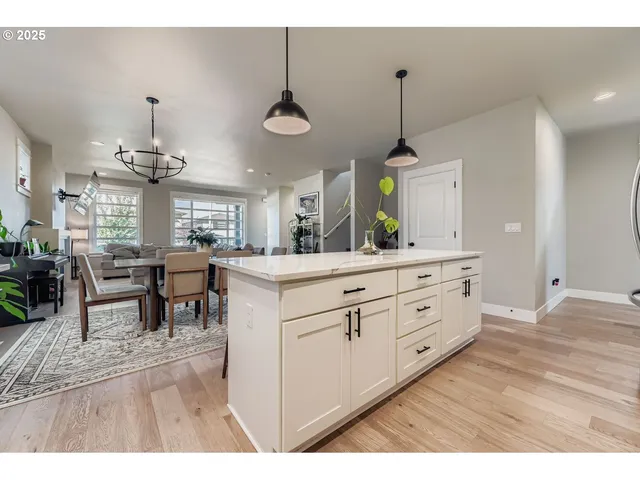 a kitchen with kitchen island granite countertop a stove a sink a dining table and chairs with wooden floor