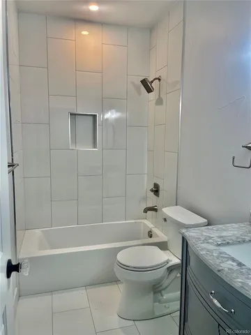 a bathroom with a granite countertop bathtub sink vanity mirror and toilet