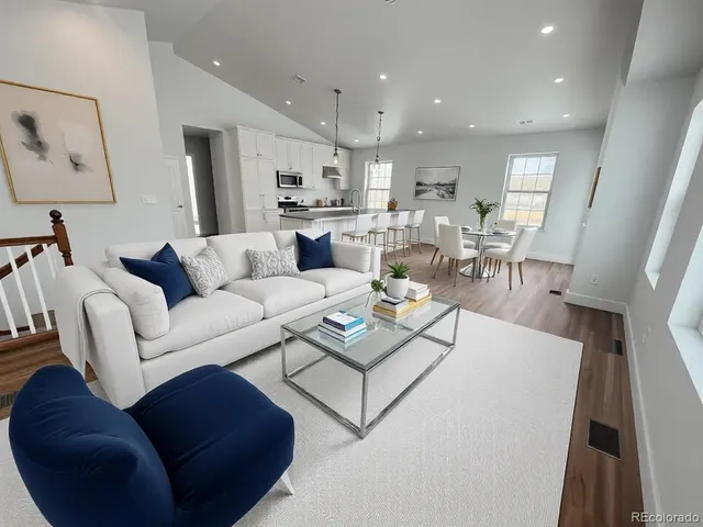 a living room with furniture white walls and a dining table with kitchen view