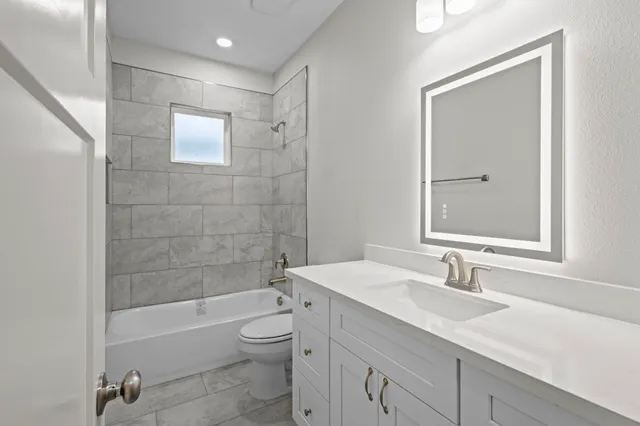 a bathroom with a granite countertop sink a toilet and shower