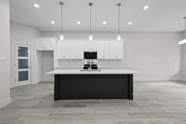 a kitchen with kitchen island granite countertop a sink a stove oven a counter space and cabinets