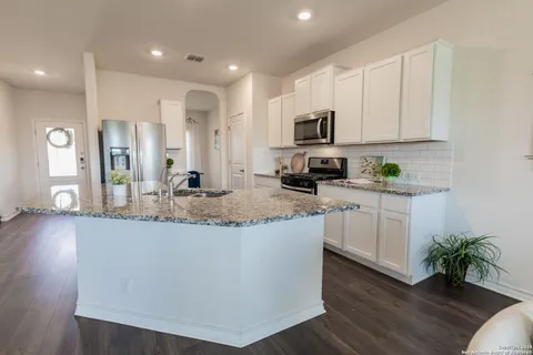 a kitchen with kitchen island granite countertop a sink a counter space and cabinets