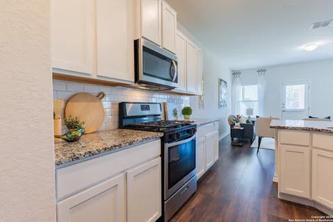 a kitchen with stainless steel appliances granite countertop a stove top oven a sink dishwasher and a refrigerator with wooden floor