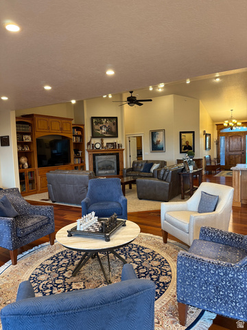 3145 South 500 West Vernal, UT 84078 - Photo 57 of 64 Living room featuring wood finished floors, a chandelier, a fireplace, and a ceiling fan