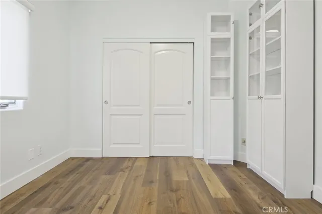 a view of an empty room with wooden floor and closet