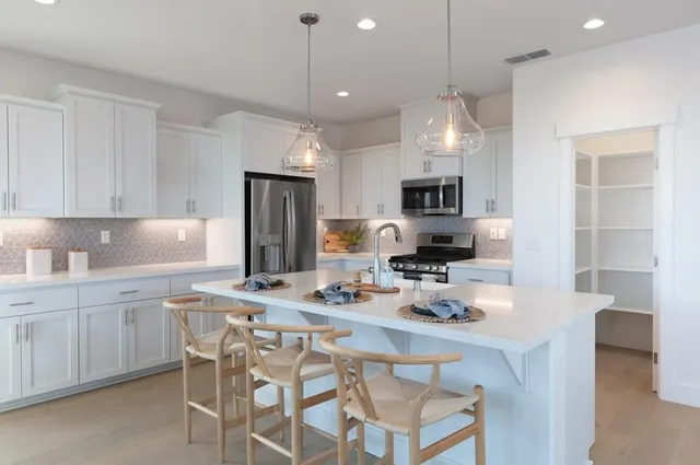 a kitchen with kitchen island granite countertop a sink stove and refrigerator