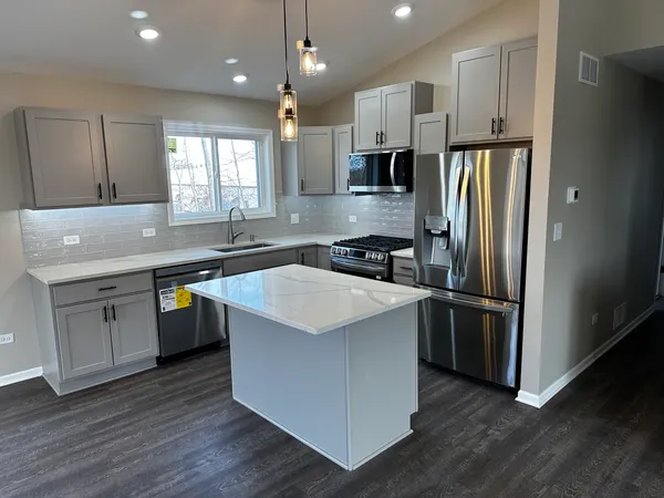 a kitchen with stainless steel appliances granite countertop a sink a refrigerator a stove a microwave and island with wooden floor