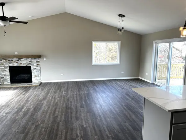 an empty room with wooden floor fireplace and windows