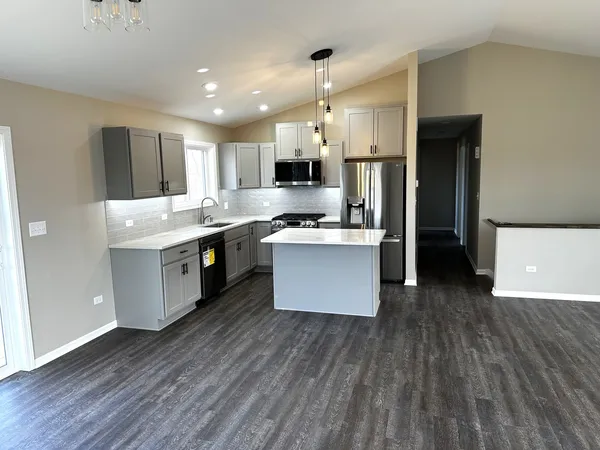 a kitchen with stainless steel appliances a kitchen island hardwood floor sink stove and wooden cabinets