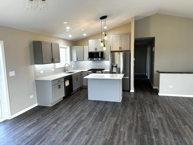 a kitchen with stainless steel appliances a kitchen island hardwood floor sink stove and wooden cabinets