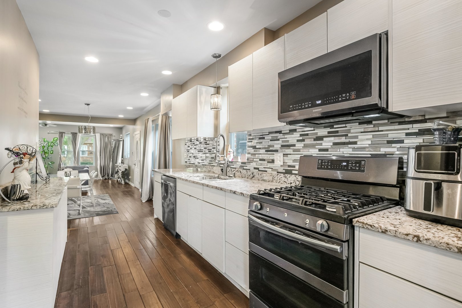1523 East 85th Street Chicago, IL 60619 - Photo 6 of 27 a kitchen with stainless steel appliances kitchen island granite countertop a stove top oven a sink dishwasher a dining table and chairs with wooden floor