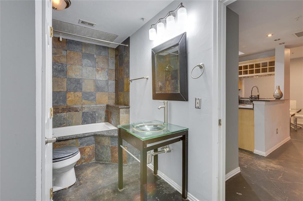 4104 North Hall Street, Unit 102 Dallas, TX 75219 - Photo 15 of 18 Bathroom featuring a slate tile shower surround with integrated bench seating, a glass vessel sink set on a metal-framed vanity, and a wall-mounted light fixture