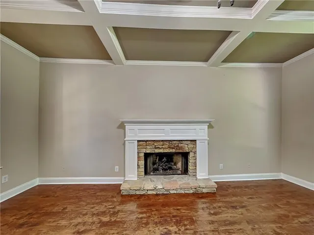 a view of an empty room with wooden floor and a fireplace